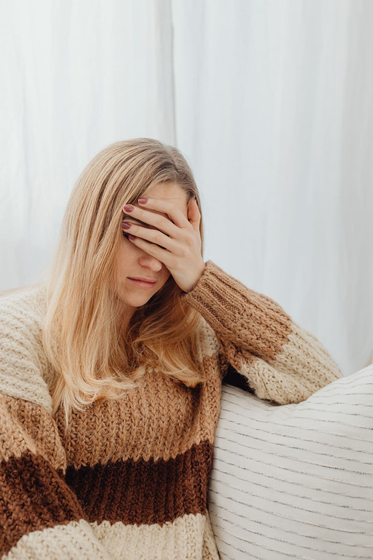 A woman in a knitted sweater resting on a sofa